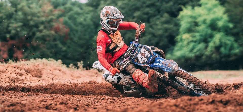 Motocross rider turning on muddy track.